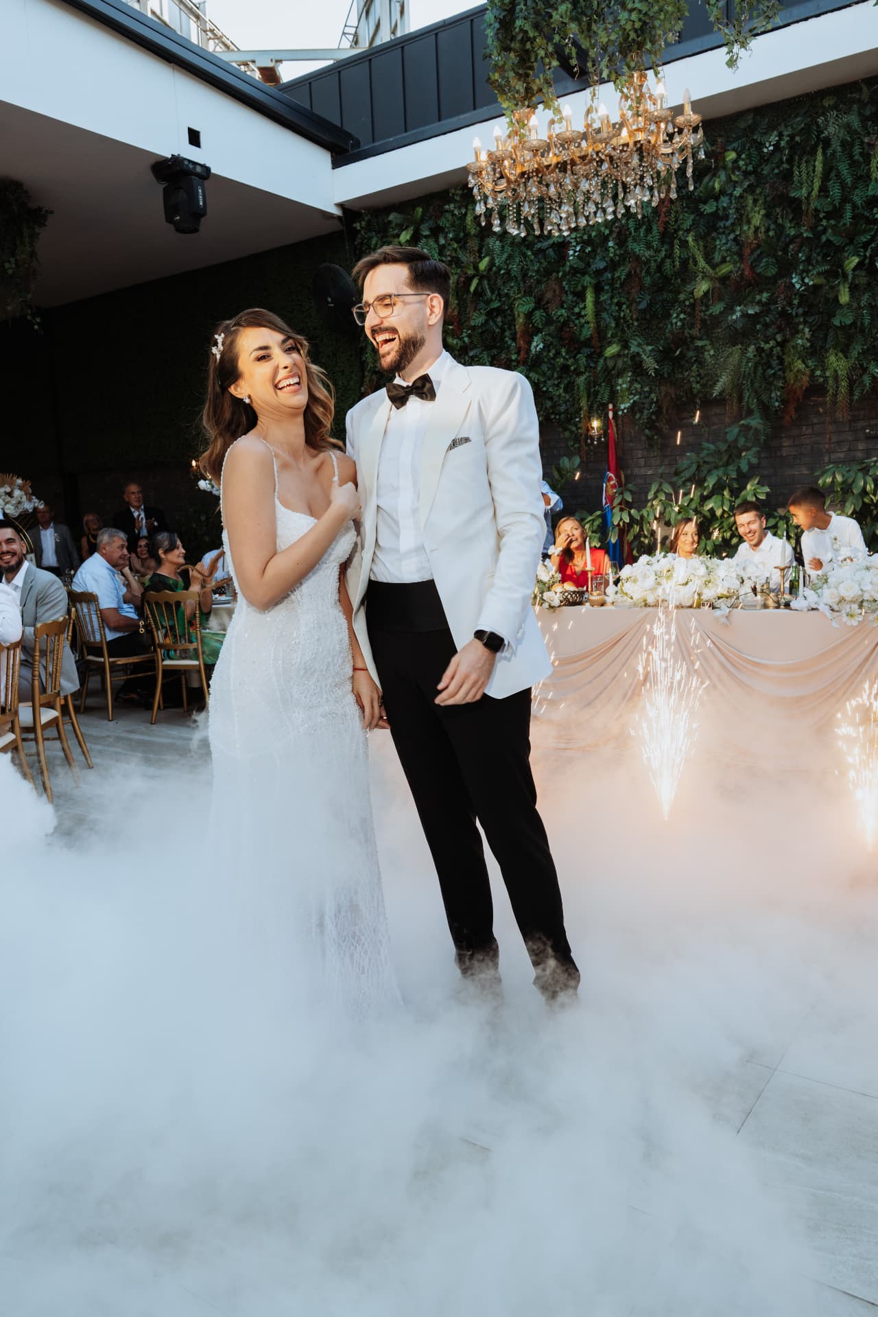 Bride and groom laughing on the dance floor amid low fog and cold sparklers at Verde Open Concept, Belgrade