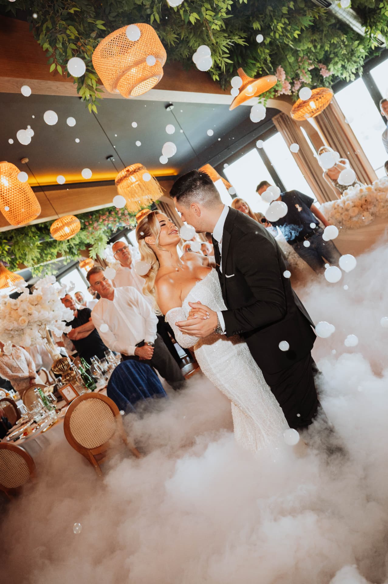 Ivana and Stefan sharing their first dance through low fog and floating bubbles at Restoran Suvenir in Novi Sad, Serbia.