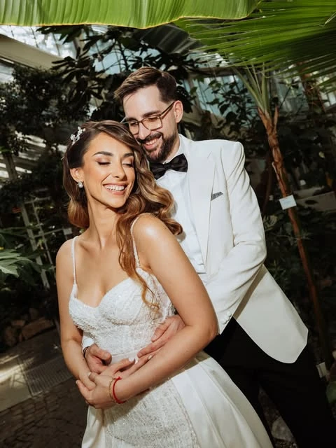 Bride and groom embracing beneath tropical leaves — wedding photography by Nemanja Potkonjak